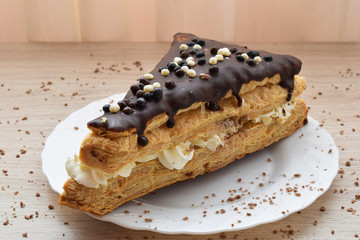 Delicious puff pastry filled with cream and covered in chocolate on a plate
