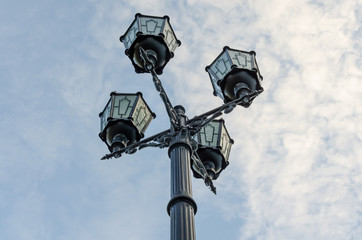 Fototapeta na wymiar A pole with four lanterns against the sky.