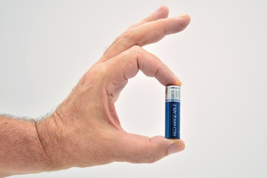 dedos de una mano sujetando una pila recargable