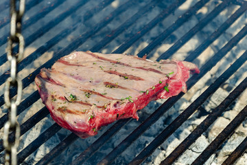A piece of red meat on the grill.