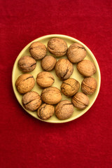 Walnuts in a plate on a red background.