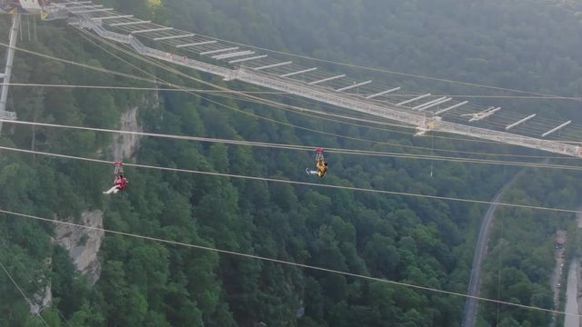 Sochi, Russia - may 2019. Aerial view two people fly on zipline on Sochi Skypark. Summer evening follow shot