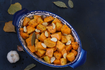 Pumpkin slices with garlic are in a ceramic form on dark background, Copy space, horizontal orientation, closeup