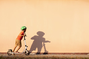 A boy puts a green helmet on his head. Bicycle helmet. Child athlete.