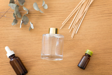 home perfume and aromatherapy concept - aroma reed diffuser, essential oil and branches of eucalyptus populus on wooden table