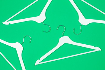 White wooden hangers on pastel green background. Shopping, sale, promo, social media, new season concept