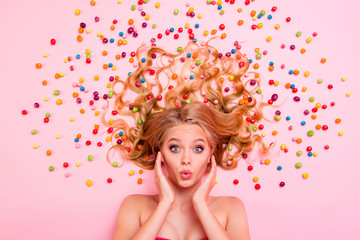 Close up top above high angle view photo beautiful glad she her lady lying down sweets ideal hair colored little candies lips together sending kisses hands arms cheeks isolated pink background