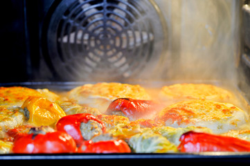 Assorted stuffed peppers, stuffed cabbage and zucchini on a baking sheet in the oven