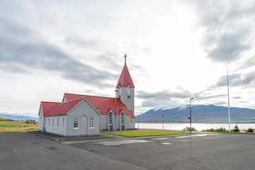 In the morning at chapel on small hill opposite Akureyri city. The Christian cross on roof top of chapel contrast with white sky waiting sunrise. - 290109892