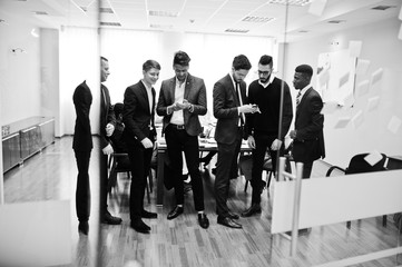 Six multiracial business mans standing at office and use mobile phones. Diverse group of male employees in formal wear with cellphones.