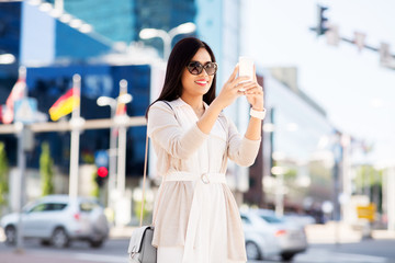 communication, lifestyle and technology concept - smiling young asian woman taking selfie by smartphone on city street