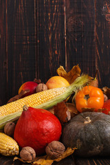 Different vegetables, pumpkins, apples, pears, nuts, tomatoes, corn, dry yellow leaves on wooden background. Autumn mood, copy space. Harvest concept.
