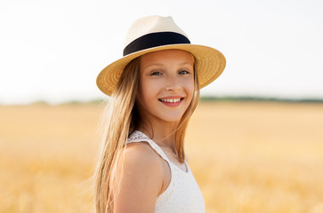 nature, fashion and people concept - portrait of smiling young girl in straw hat on cereal field in summer