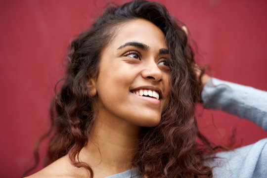 Close up beautiful young woman with nose ring smiling against red wall