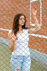 Fototapeta na wymiar portrait of a girl in a white T-shirt near a metal grid