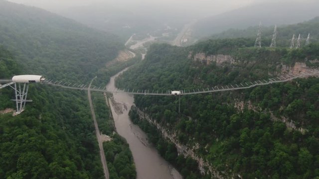 Sochi, Russia - may 2019. Aerial view fly around SkyBridge Suspension bridge in Skypark Sochi AJ hackett. Mountain valley with light haze on a background