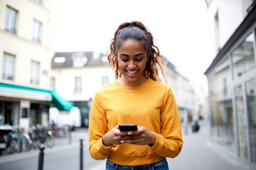happy Indian girl looking at mobile phone in city