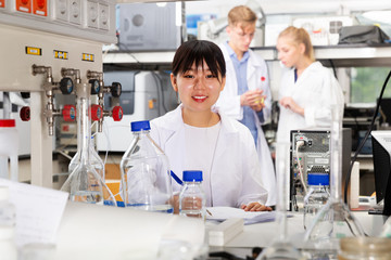 Chinese woman lab technician noting results in test chart