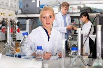 Fototapeta premium Female student writing report on chemical experiments