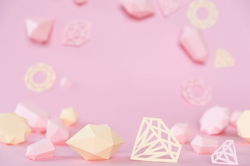 A variety of faceted gemstones, made of paper on a pink background.