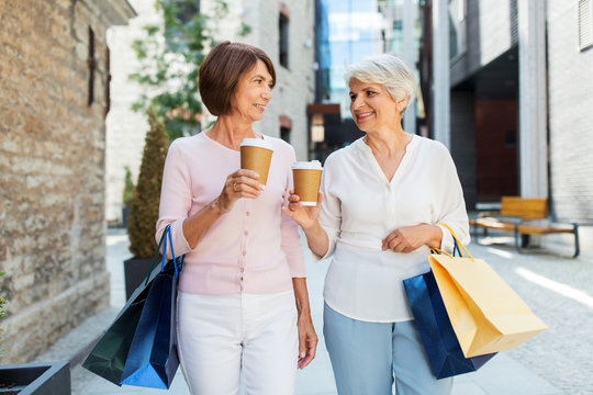 Sale, Consumerism And People Concept - Two Senior Women Or Friends With Shopping Bags Drinking Takeaway Coffee On Tallinn City Street