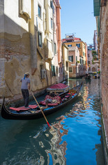Fototapeta na wymiar Narrow canal in Venice, Italy, with gondolas and historic houses, in a beautiful sunny day.
