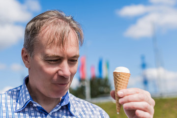 Happy elderly (50 years old) man in a shirt and tie eating ice cream at summer day. Concept