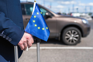 Man in a blue suit with a suitcase and Europe or European(EU)  flag at the airport parking on the...