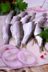 Salted sprats carcass served on piece of parchment with parsley and red onion