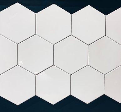 real photo of glossy white hexagonal tiles wall on black background isolated. geometric pattern, abstraction