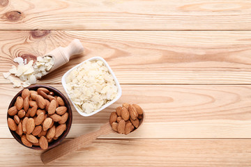 Almonds in bowls and spoon on brown wooden table