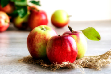 Ripe organic apples on jute fabric on a light background.