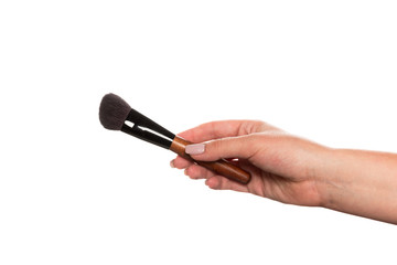 Cosmetic brush for makeup in a female hand isolated on white background.