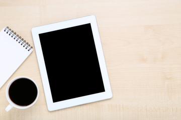 Tablet computer with notepad and cup of coffee on wooden table