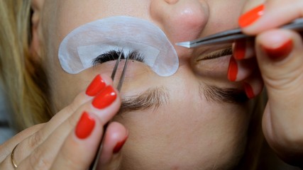 Eyelash extension procedure. The master grows long eyelashes. Female with extended eyelashes