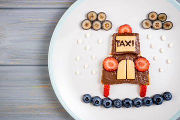 Children's breakfast with sandwich and berries. Funny taxi car sandwich with chocolate paste, berries and cheese. Kids food idea.  Top view