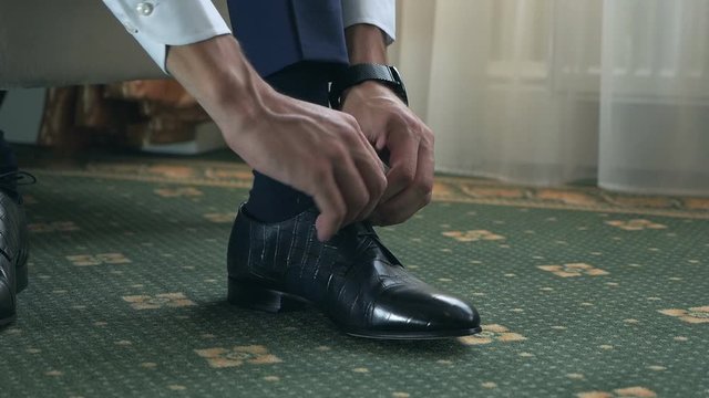 Groom puts on shoes on wedding day