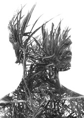 Double exposure of a young handsome man’s portrait blended with tropical leaves, showing the...