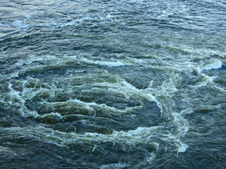 Rough churning water with whirlpool and white foam crests