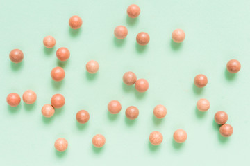 Creative flat lay cosmetics background, blush balls and cosmetic brushes on neo-mint color background.