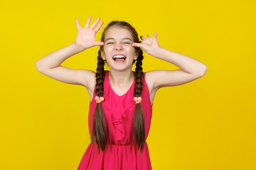 Fototapeta na wymiar Beautiful young girl in pink dress on yellow background