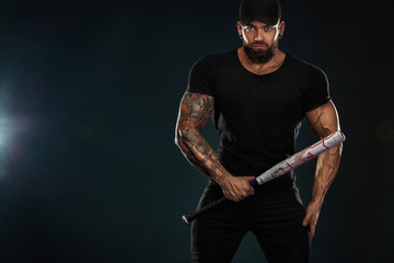 Strong and fit man bodybuilder with baseball bat in black t-shirt. Sporty muscular guy athlete....