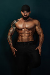 Fototapeta na wymiar Strong and fit man bodybuilder bare-chested in black baseball cap. Sporty muscular guy athlete. Sport and fitness concept. Men's fashion.