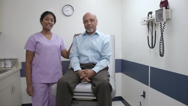 Nurse and patient in hospital or doctor office exam room looking at camera