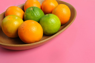 Orange, yellow, green fruit.Clean color plate, brown.Stoned pink background.Close up