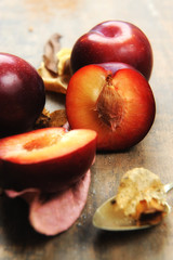 Fototapeta na wymiar Half plum fruit, pitted, unfocused.Second flat, plum, focused.Tasteful.Age wood color background.Close up.No one.