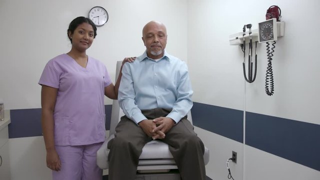 Patient and nurse in hospital or doctor office exam room looking at camera