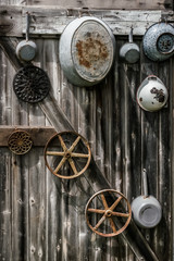 Group of rustic cookware, pots, pans, colander, hung on a weathered barn board wall - still life