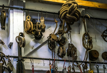 A group of rusty lifting wheels, rusted pulleys hanging on side wall of barn workshop with exposed beams