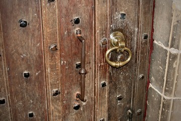 close up of old oak door with brass knocker 